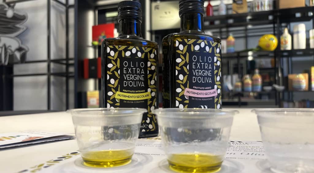 Bottiglie di olio extravergine Coratina e Peranzana con bicchieri per l'assaggio guidato al Frantoio Muraglia