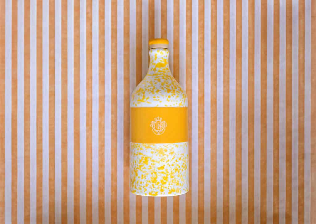 Dettaglio dell'orcio Acqua di Parma: ceramica a schizzi gialli, stemma della Maison e tappo sigillato a cera
